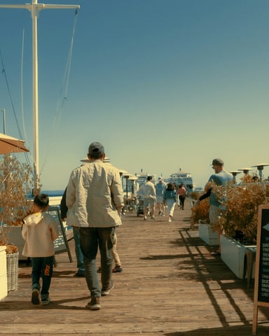 Sunny pier with oceanfront café and people walking along the waterfront