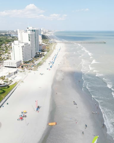 Aerial view of Myrtle Beach coastline with condos, pier, and wide sandy beach