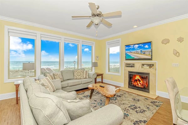 Beachfront resort building with ocean view, bedroom with turquoise headboard, oceanfront balcony seating, and kitchen-dining area