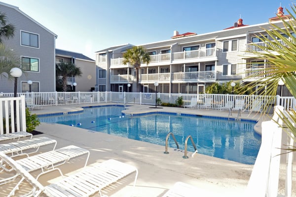 Oceanfront resort with beachfront balcony, multi-story building, living room with ocean views, and swimming pool area.