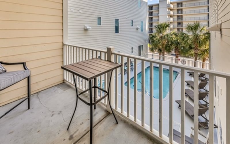 Balcony with high-top table overlooking swimming pool and neighboring buildings